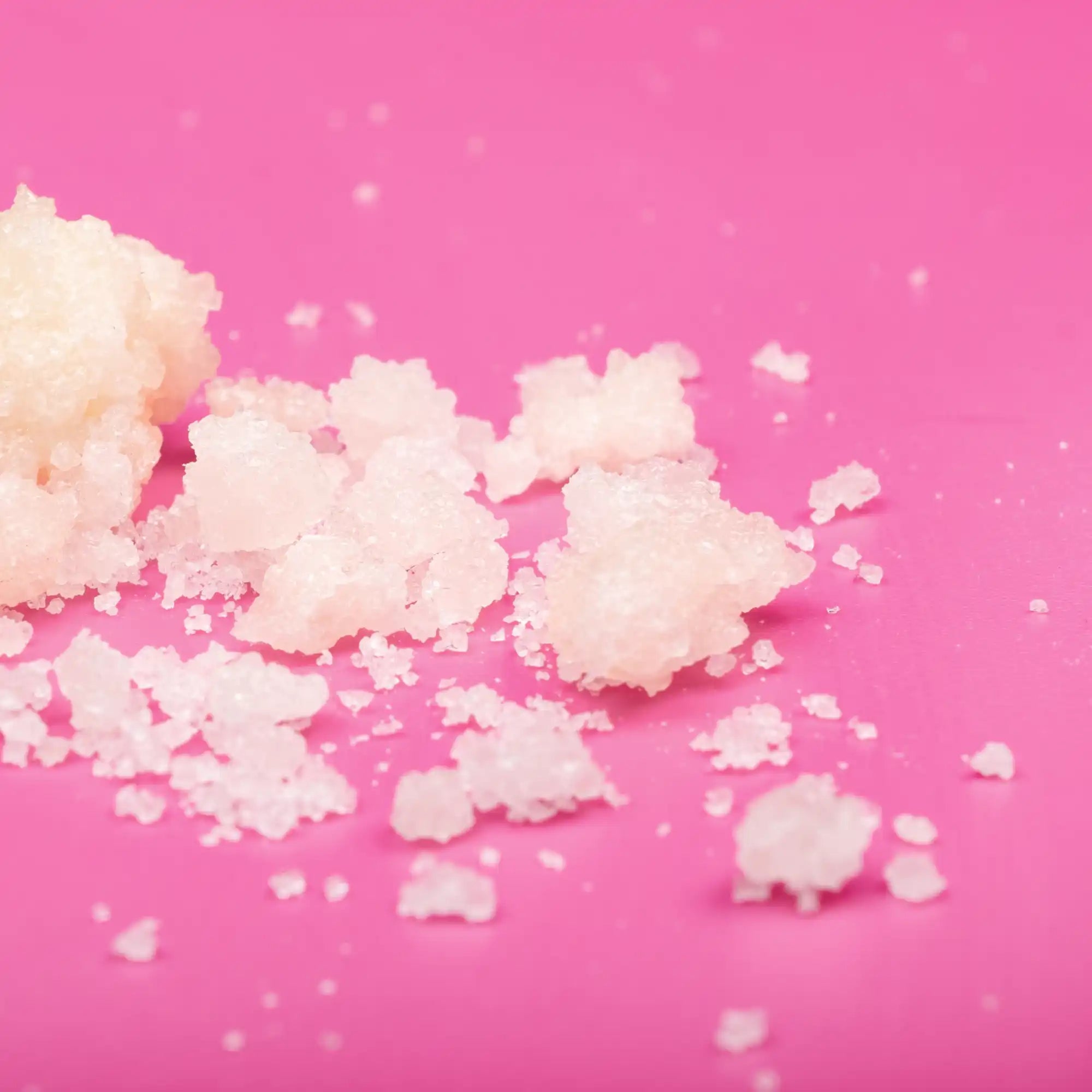 Clumps of white, powdery substance scattered on a pink surface.