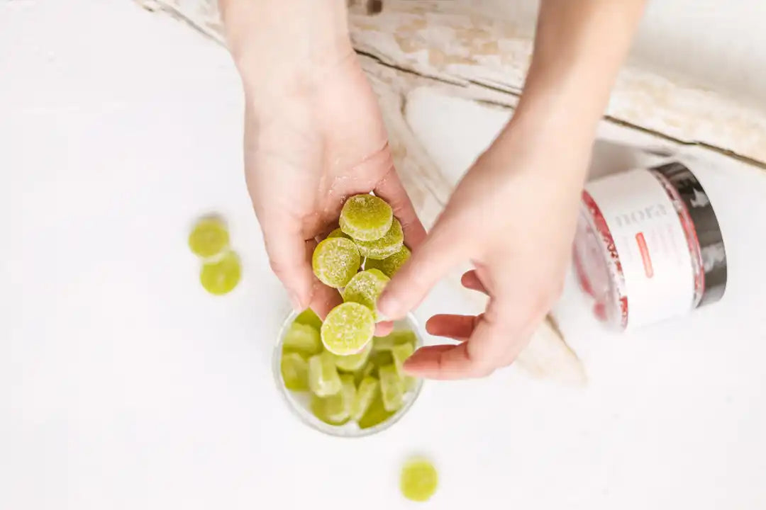 Hands squeezing lime slices into a glass.