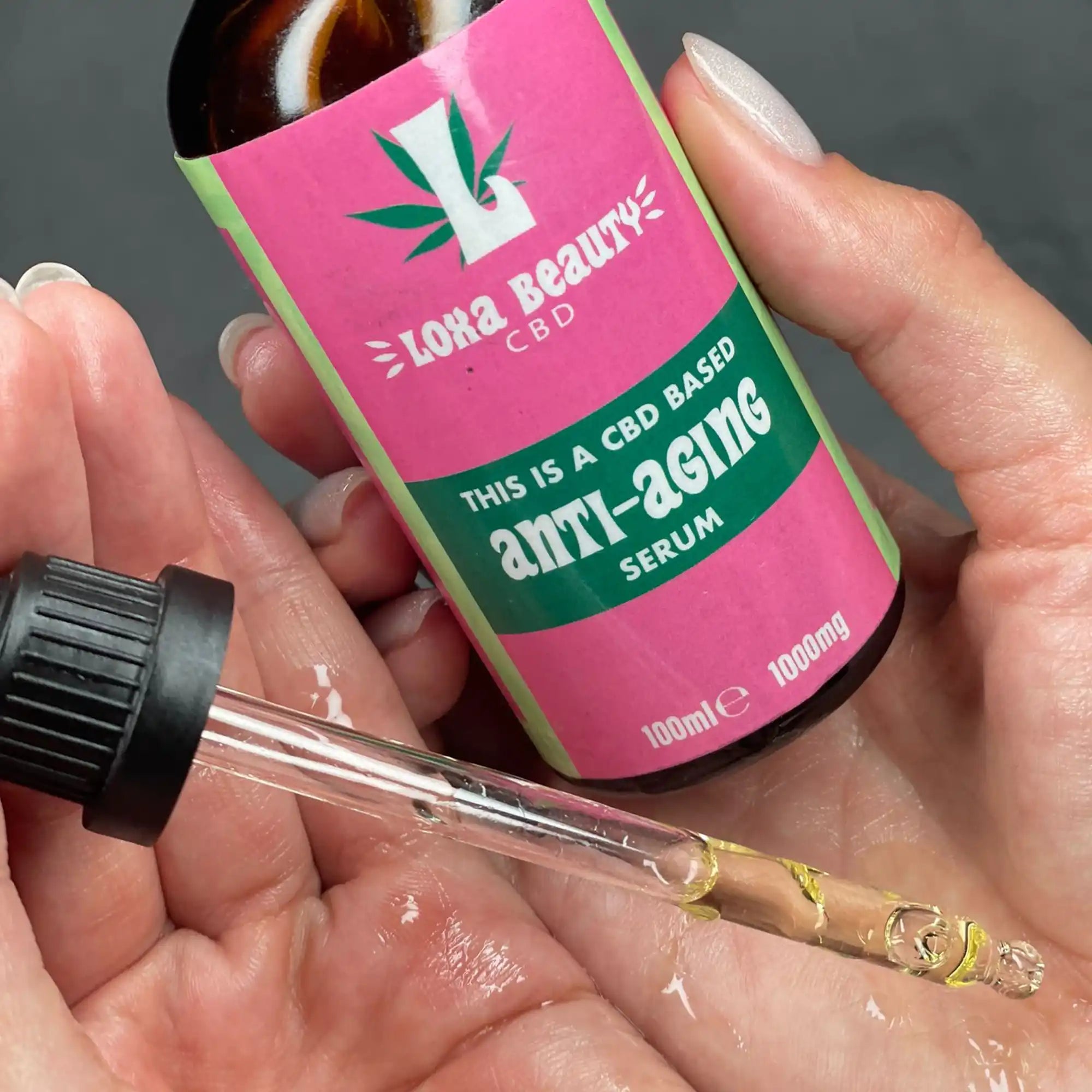 Pink and green bottle of CBD anti-aging serum with a dropper.