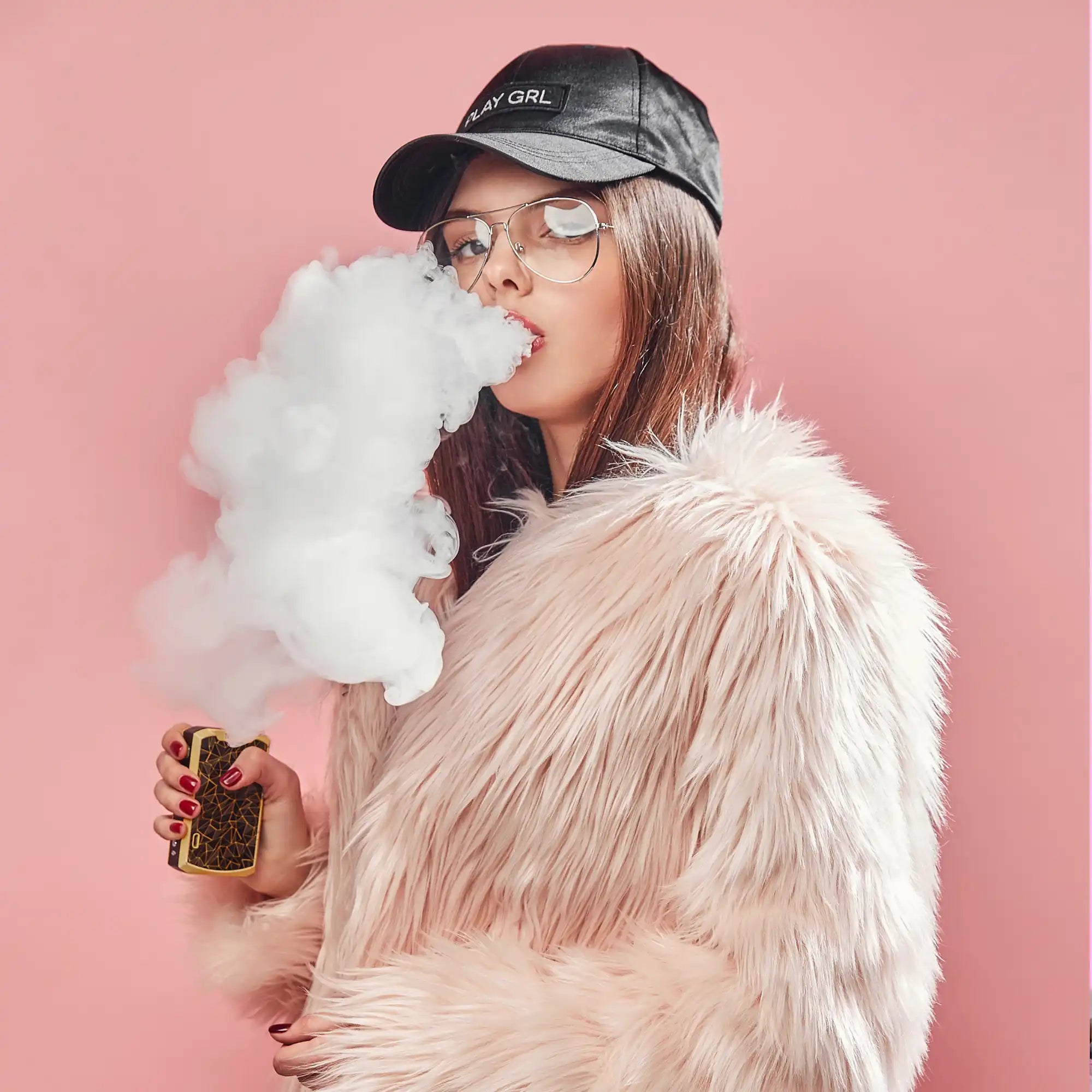 Woman wearing a black cap and furry white jacket exhaling vapor from an electronic cigarette.